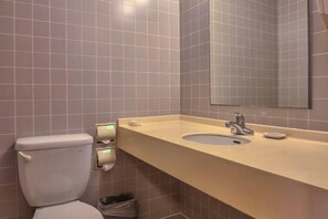 A bathroom with a toilet, sink, and mirror. - Jinjiang Hotel (Taizhou Huangyan Jiufeng Park) (Taizhou)