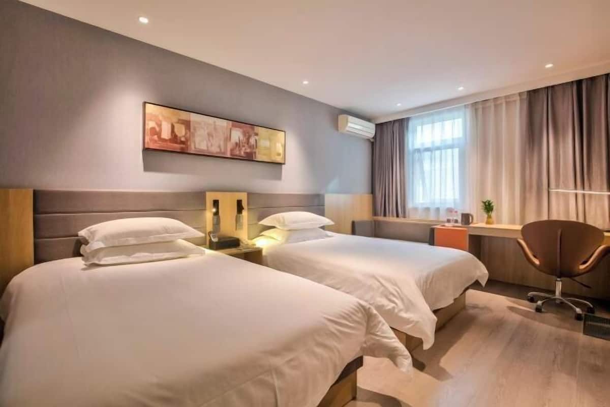 A hotel room with two beds, a desk, a chair, and a painting on the wall.