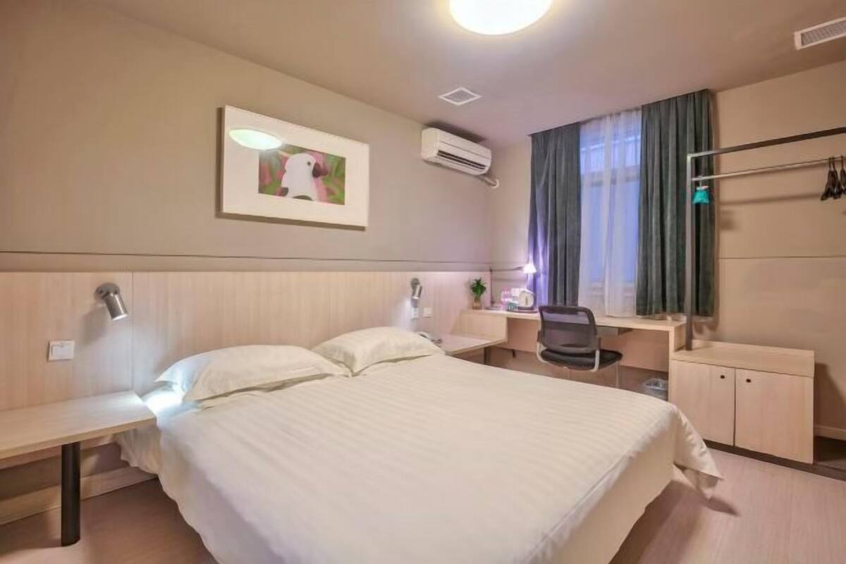 A hotel room with a bed, desk, chair, and wardrobe.