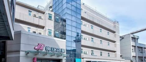 Edifício moderno com fachada de vidro e sinalização indicando uso comercial.