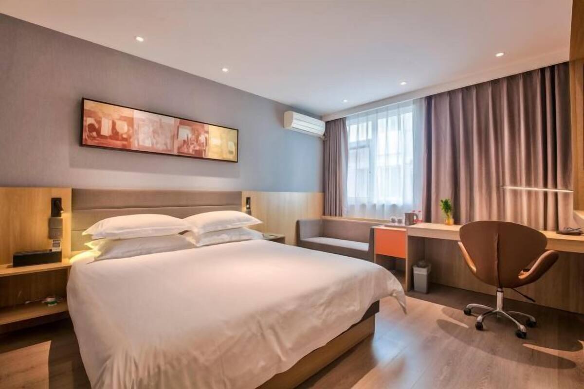A modern hotel room with a large bed, a desk, and a chair.