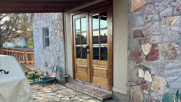 Ein Steinhaus mit Holztür und überdachter Terrasse.