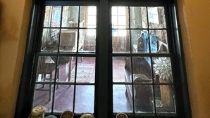 Ein Zimmer mit einem großen Fenster, einer Holzbalkendecke und einem Kuhschädel, der über dem Fenster angebracht ist.