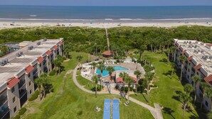 Luftaufnahme eines Hotels mit Pool, Tennisplatz und Zugang zum Strand.