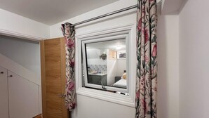 A room with a small window, wooden door, and a view of a kitchen area. - Central Luton Executive Suite (Luton)