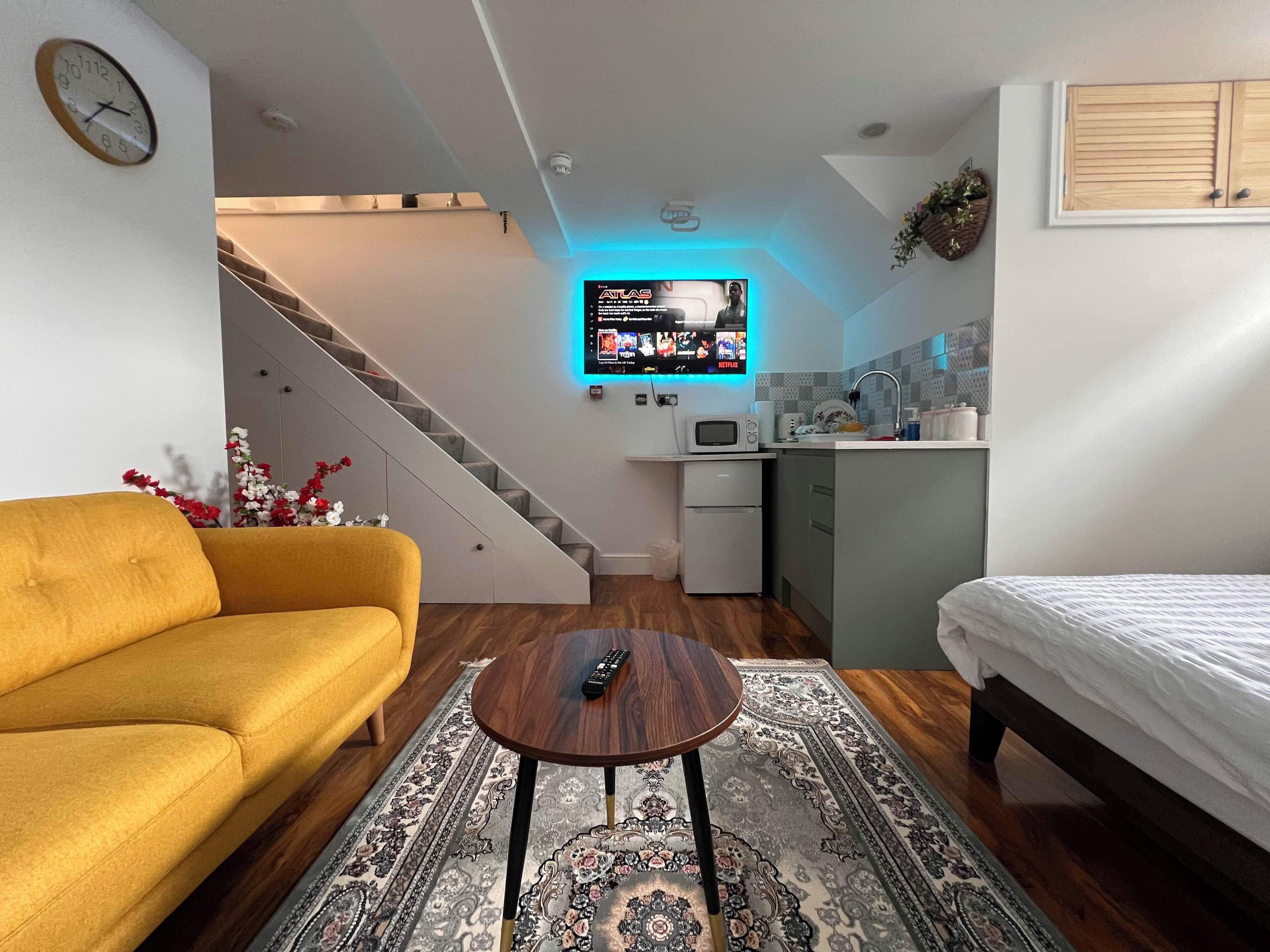 Una sala de estar moderna con un sofá, una mesa de centro y un televisor que muestra un servicio de streaming.