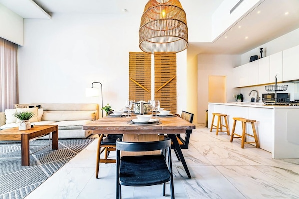 A modern kitchen with white cabinets, a wooden island, and a hanging light fixture. - Elevate Your Vacation in Cabo Luxury Best Location (Cabo San Lucas)