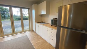 Eine moderne Küche mit einem Edelstahl-Kühlschrank, Holzschränken und einer Glastür, die auf eine Terrasse führt.