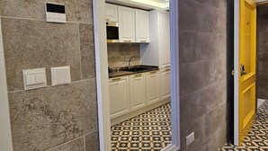A modern kitchen with white cabinets and a black countertop, a patterned floor, and a large mirror on the wall. - Balcony Hotel (St. Julian's)