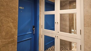 A blue door with the number 402, a white cabinet with glass doors, and a tiled floor. - Balcony Hotel (St. Julian's)