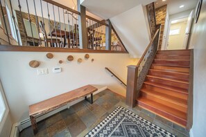 A staircase with wooden steps and metal railings, a wooden bench, and a patterned rug on the floor. - Enclave 17 (Keystone)