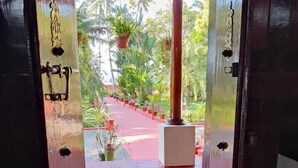 A doorway leading to a covered outdoor area with potted plants and a red floor. - Tentgram Alleppey Riverfront  (Vaikom)