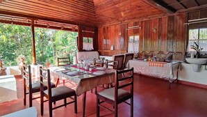 A wooden dining area with a table set for four, surrounded by chairs. - Tentgram Alleppey Riverfront  (Vaikom)