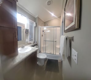 A bathroom with two sinks, a shower, and a toilet.