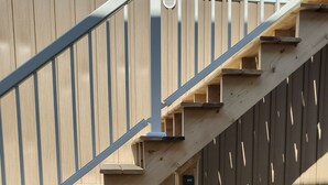 Un escalier en bois avec des rampes métalliques menant à une terrasse.