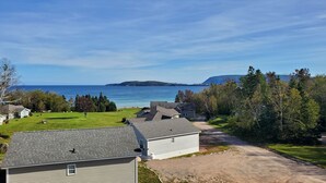 Une zone résidentielle côtière avec des maisons, un chemin de terre et une vue sur la mer et une île lointaine.