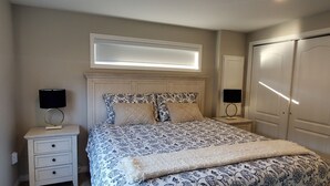 Une chambre à coucher comprenant un lit, deux tables de chevet, une commode, une fenêtre avec des stores et une armoire.