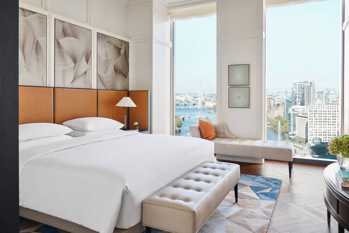 Ein modernes Hotelzimmer mit einem großen Bett, einer Sitzecke mit Blick auf die Stadt und Kunstwerken an den Wänden.
