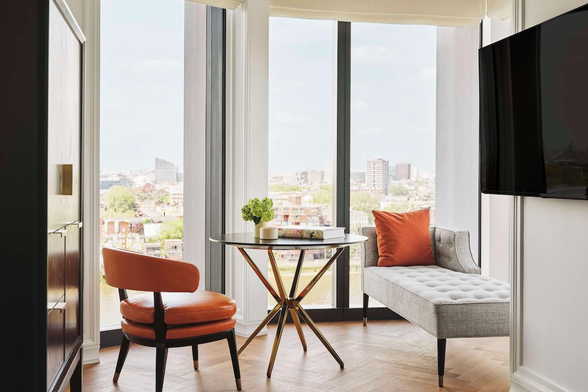 Ein modernes Wohnzimmer mit großem Fenster, einem runden Tisch, einer Couch und einem Fernseher.