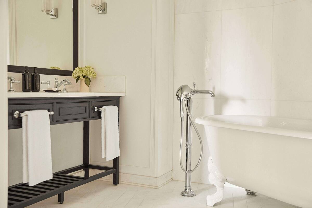 Ein modernes Badezimmer mit einer weißen Badewanne, einem schwarzen Waschtisch mit Spiegel und einem weißen Handtuchhalter.