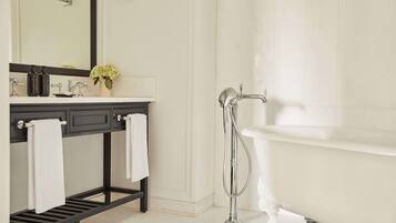 Une salle de bain moderne avec une baignoire blanche, un meuble-lavabo noir avec un miroir et un porte-serviettes blanc.