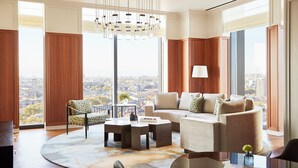 Een moderne woonkamer met een groot raam, een ronde salontafel, een bank en een fauteuil.