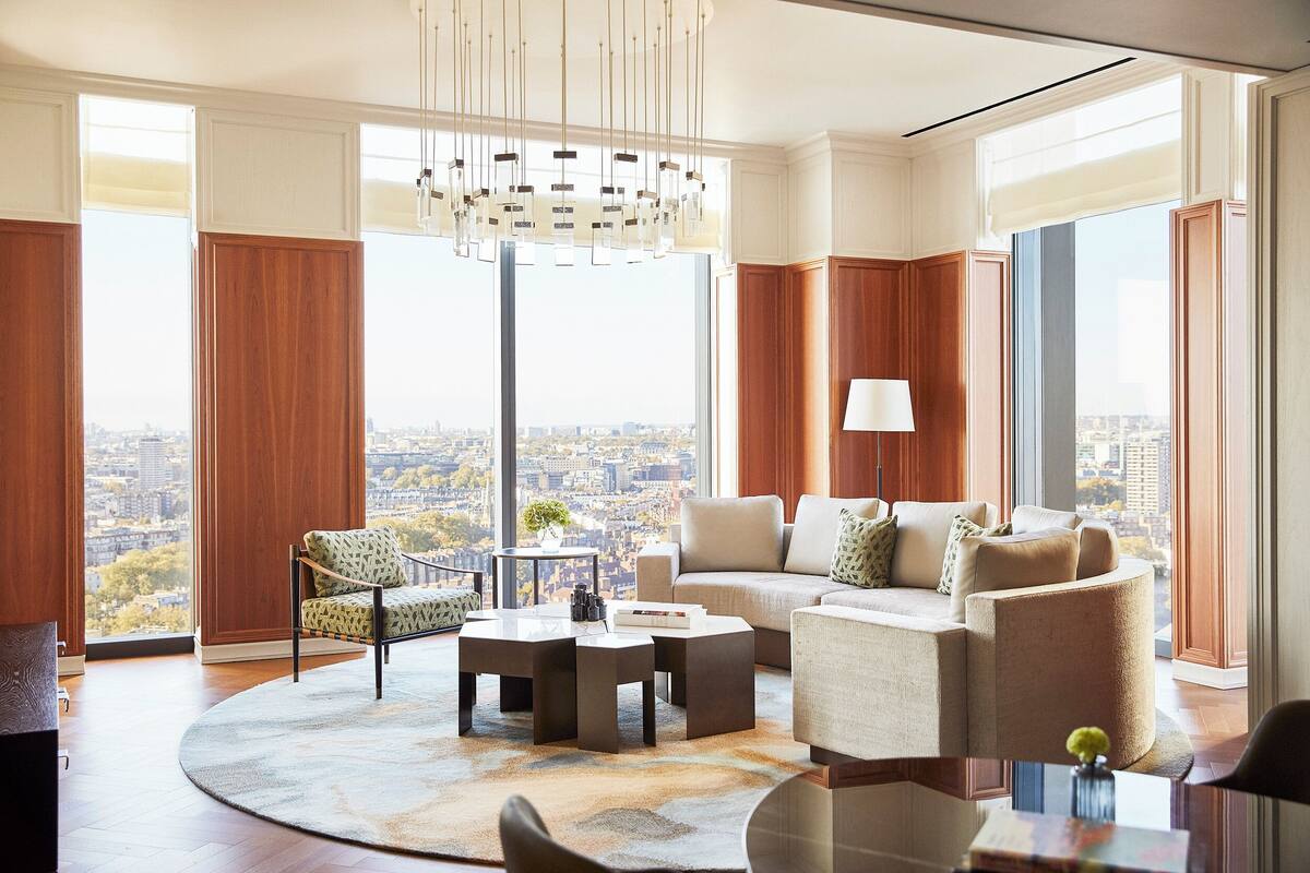 Ein modernes Wohnzimmer mit großem Fenster, einem runden Couchtisch, einer Couch und einem Sessel.
