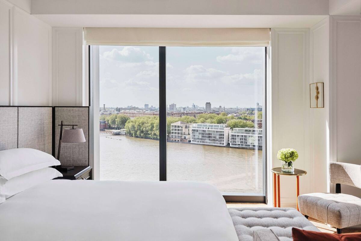Ein Hotelzimmer mit großem Fenster und Blick auf einen Fluss und die Stadtlandschaft.