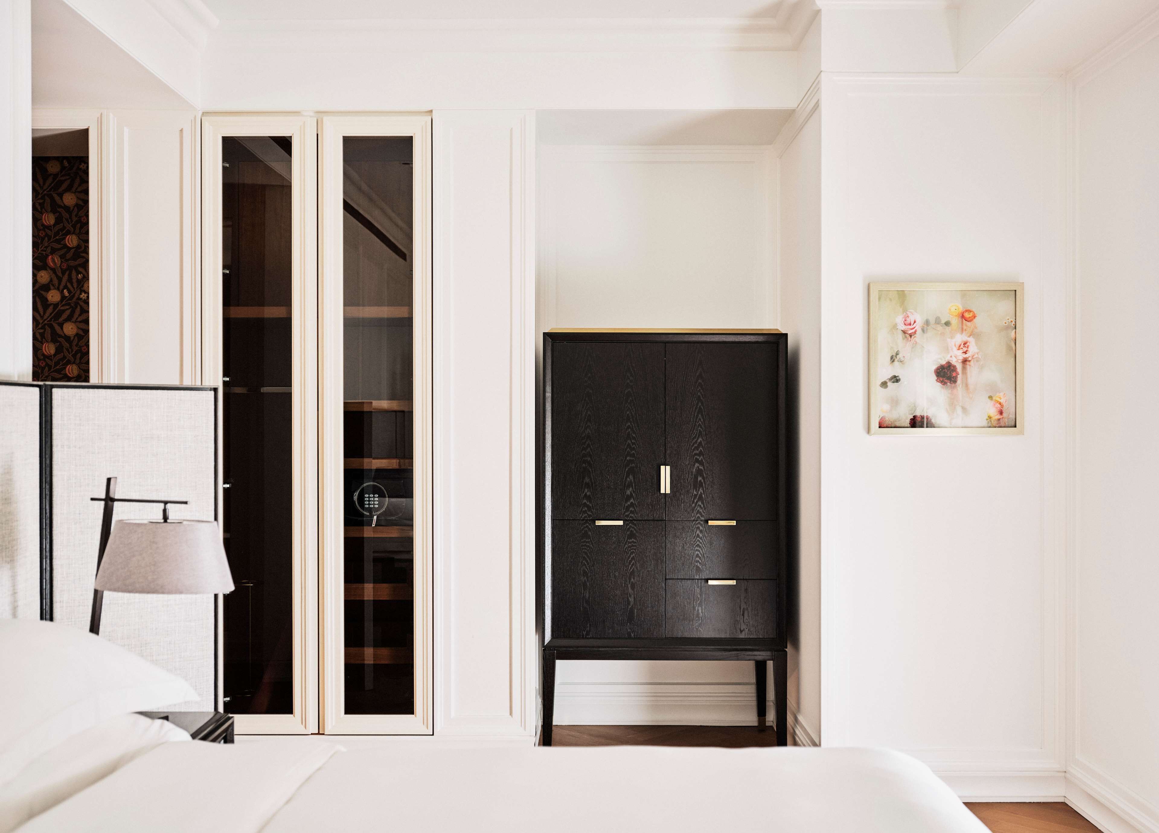 Quarto com cama, luminária de cabeceira, guarda-roupa e um quadro na parede.