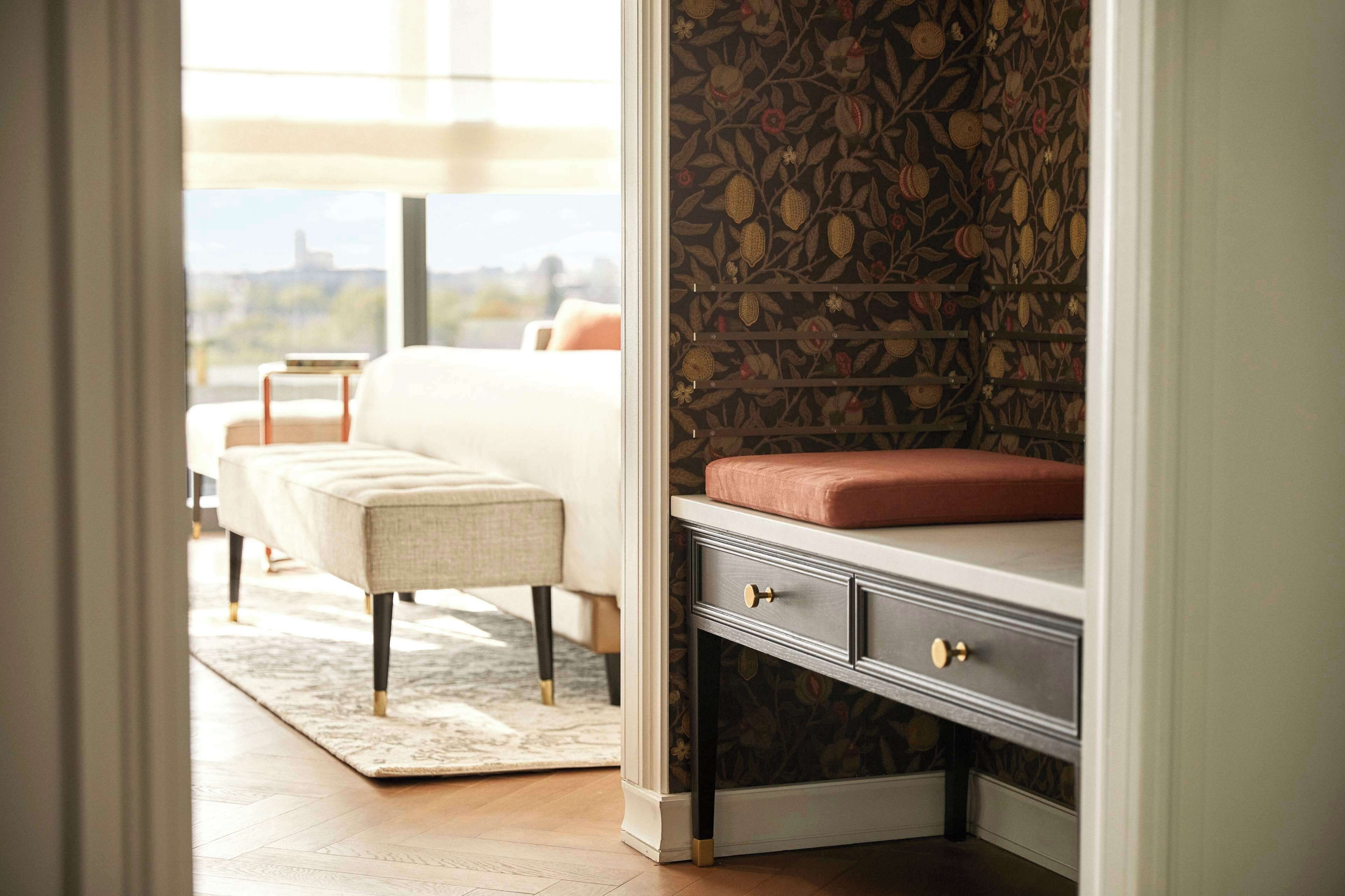A bedroom with a bed, a bench, and a dresser with drawers.