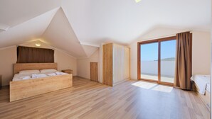 Ein geräumiges Schlafzimmer mit einem großen Bett, einem Kleiderschrank und einer Glastür zum Balkon.