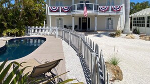 A two-story house with a pool, a white picket fence, and an American flag. - Family vacation on AMI w/pool 4BR, 2.5BA, up to 8 guests (Holmes Beach)