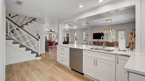 A modern kitchen with white cabinetry, a stainless steel dishwasher, and a large island with a sink. - Family vacation on AMI w/pool 4BR, 2.5BA, up to 8 guests (Holmes Beach)