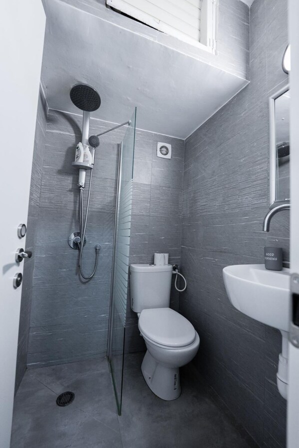 A compact, modern bathroom with a shower, toilet, and sink.