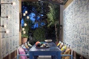 Enjoy meals al fresco in this charming outdoor dining area, surrounded by vibrant botanical art and lush greenery.