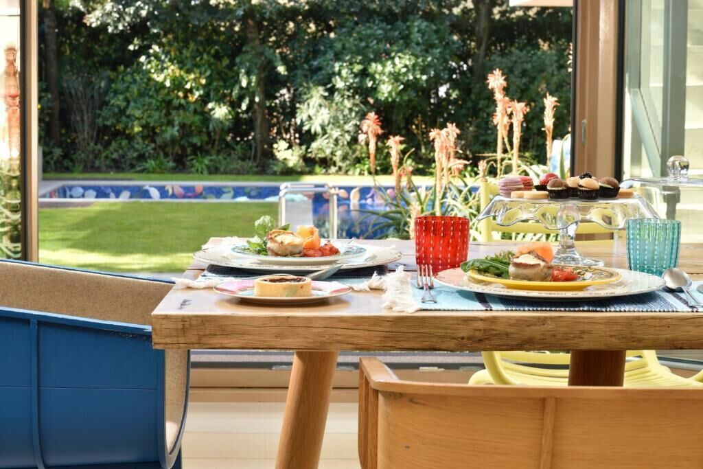Un espace de restauration en plein air avec une table dressée pour deux personnes, entouré de verdure et offrant une vue sur la piscine.