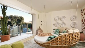 A modern room with a hanging chair, a large window, and a cactus plant. -  Magic Forte (Forte dei Marmi)