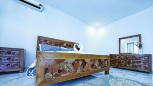 A bedroom with a stone-patterned bed, a wooden dresser, and a mirror on the wall. - Luxury Villa Tavares Bautistas (Puerto Plata)