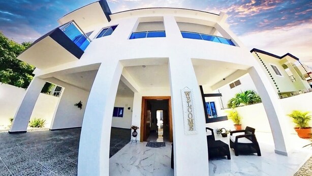 A modern, multi-level building with a curved facade, large windows, and a welcoming entrance. - Luxury Villa Tavares Bautistas (Puerto Plata)