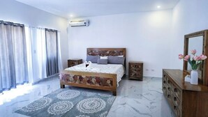 A bedroom with a bed, bedside tables, a dresser, a mirror, and a window with curtains. - Luxury Villa Tavares Bautistas (Puerto Plata)