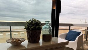 Un balcon avec un pot de fleurs, une bouteille en verre et un bol de collations.
