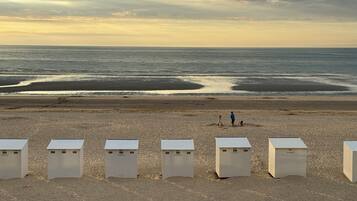 A beach with white structures, possibly beach huts, and a few people in the distance.