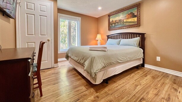 Um quarto com uma cama, uma escrivaninha, uma cadeira, uma porta e uma janela.