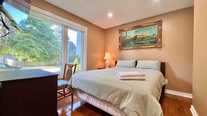 Quarto com cama, escrivaninha, cadeira, luminária e um quadro na parede.