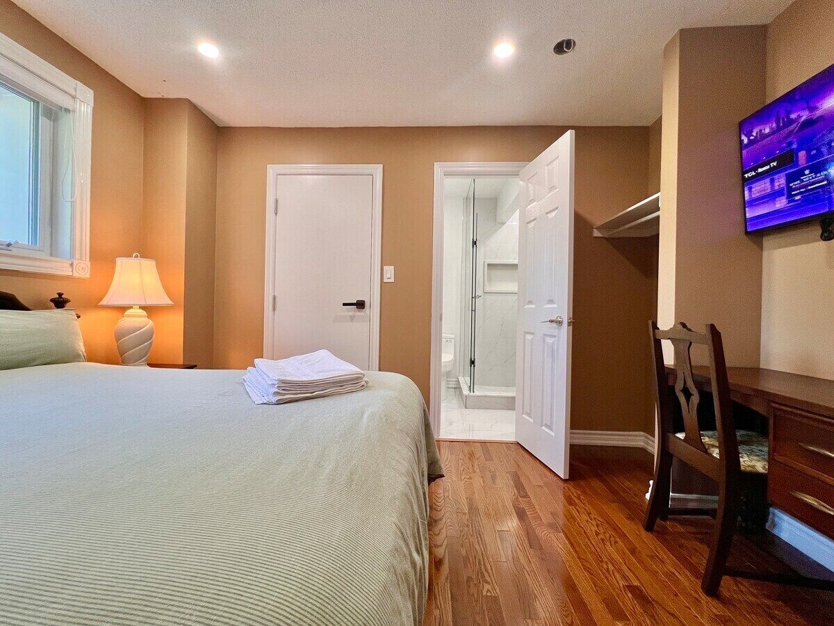 A hotel room with a bed, a desk, a chair, a TV, and a bathroom door.