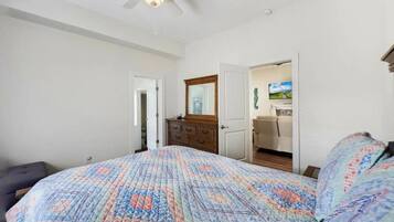 A bedroom with a large bed, a dresser, and a ceiling fan.
