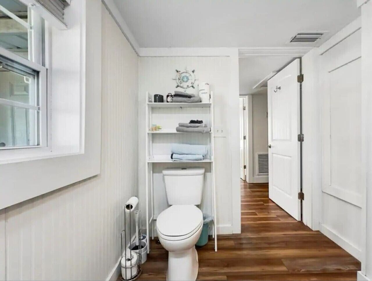 Ein schmaler Flur mit Toilette, Heizkörper und einem Regal mit Handtüchern.