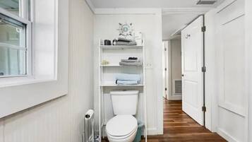 Ein schmaler Flur mit Toilette, Heizkörper und einem Regal mit Handtüchern.