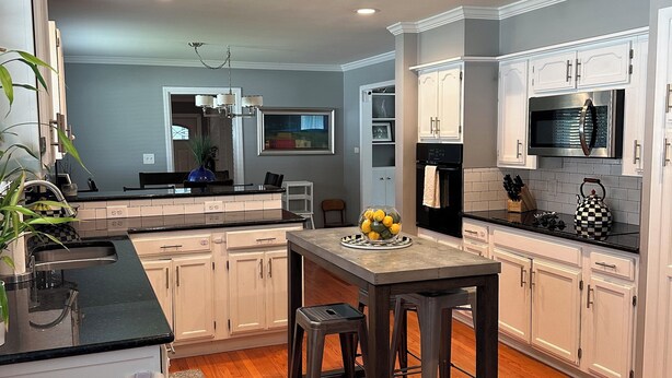 A modern kitchen with white cabinetry, a central island, and a dining area.