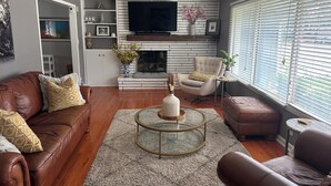 A modern living room with a leather sofa, a round coffee table, and a comfortable armchair.